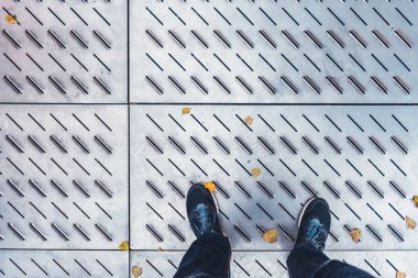 Adam çelik zemindeki siyah ayakkabılarına bakıyor.