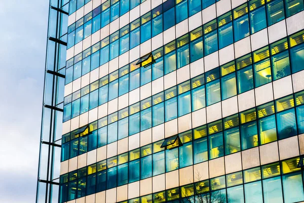 high contrasted glass facade of finance building with yellow lights inside