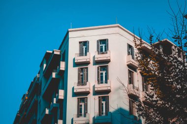 white colored corner building with darken tree on the side