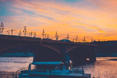 the margarete bridge at budapest, hungary with beautiful afternoon sunlight and a boat in the foreground