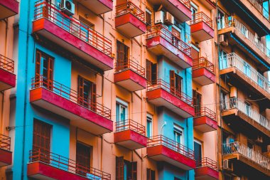 Çelik balkonu olan mavi ve kırmızı renkli bir apartman.