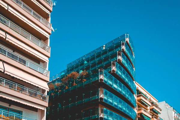 modern glass apartment building with big balcony between two older houses