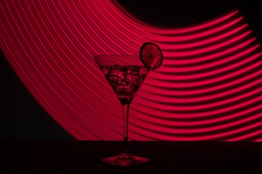 Buzlu ve neon ışıkta zeytinli bir bardak martini.