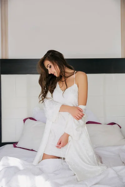 Otel odasında yatağın üstüne elbiseli ilginç kız — Stok fotoğraf
