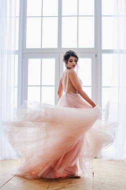 Lüks pembe elbiseli güzel kız pencerenin duruyor