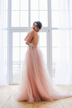 Lüks pembe elbiseli güzel kız pencerenin duruyor