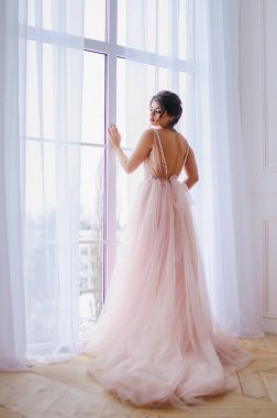 Lüks pembe elbiseli güzel kız pencerenin duruyor