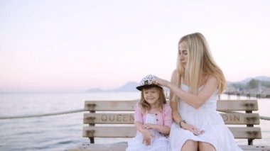 Anne ve kızı iskelede beach bankta oturmuş