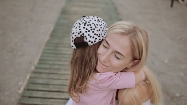 Young mother with her little daughter kissing on pier near sea — Stock Video