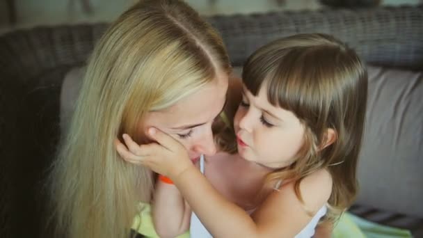 Junge Mutter mit ihrer kleinen Tochter küsst auf dem Sofa — Stockvideo