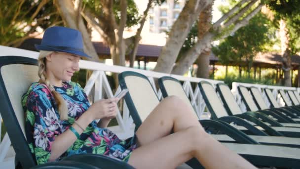 Giovane donna che utilizza il cellulare mentre sdraiato sul lettino in hotel — Video Stock