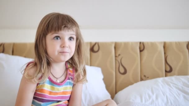 Adorable enfant en robe colorée regardant la télévision sur le lit — Video