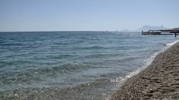 Ondas em uma praia de calhau close-up com reflexo do sol nas ondas, Mar Mediterrâneo — Vídeo de Stock