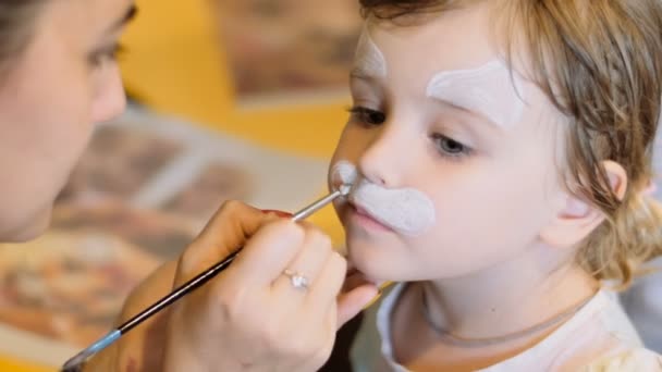 Niña conseguir pintado la cara como un gato para un carnaval — Vídeo de stock