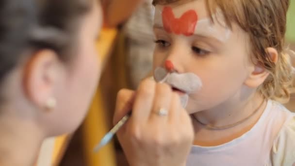 Niña conseguir pintado la cara como un gato para un carnaval — Vídeos de Stock