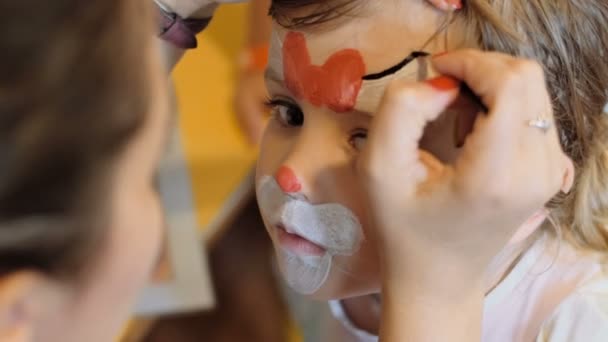 Kleines Mädchen bekommt für den Karneval ein Katzengesicht geschminkt — Stockvideo