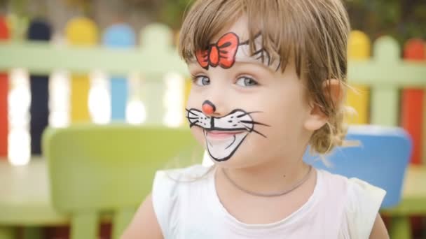 Niña conseguir pintado la cara como un gato para un carnaval — Vídeo de stock