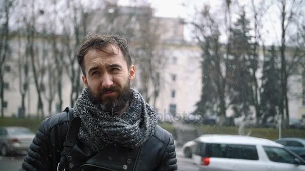 Trauriger junger Mann mit Bart in der Stadt bei Schneesturm — Stockvideo