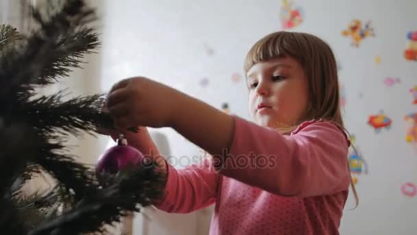 Söpö pieni tyttö koristaa joulukuusi . — kuvapankkivideo