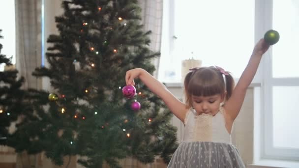 Een klein meisje speelt met kerstballen — Stockvideo