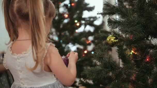 Petite fille mignonne décore le sapin de Noël . — Video