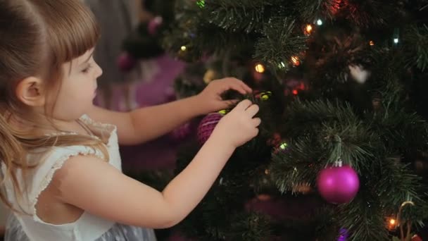 Menina bonito decora a árvore de Natal . — Vídeo de Stock