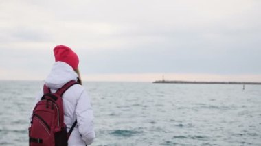 Sırt çantası ile ceketli güzel genç kadın yürümek Harbor'da rıhtımda. Bağlantı noktası çekici kadın turist ziyaret etti
