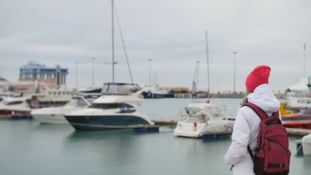 Jeune belle fille caucasienne debout sur une jetée avec des bateaux — Video