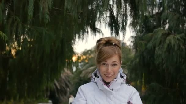 Portrait of smiling woman enjoying spring time. Woman wearing warm clothes in a green forest. Trees on background — Stock Video