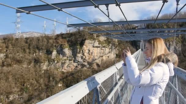 Mujer tomar fotos de los paisajes vistas de la naturaleza en el puente aéreo sobre el cañón — Vídeos de Stock