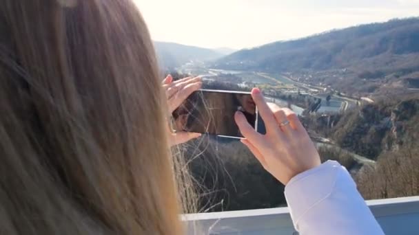 Женщина фотографирует пейзажи природы на мосту через каньон — стоковое видео