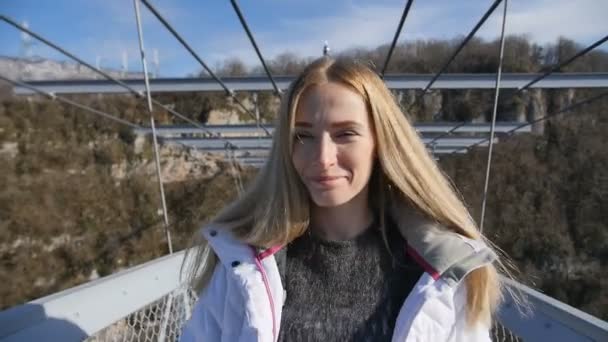 Vrouw lopen vooruit t/m hoge brug over de canyon voor de camera — Stockvideo