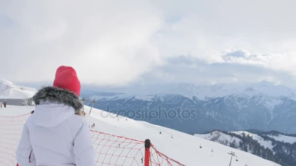 Frau in den Bergen blickt auf schöne Aussicht im Skigebiet — Stockvideo