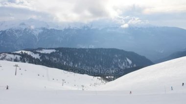 Bir grup insan kar yamaç tarafından Kayak ve snowboard binmek, dağın zirvesine görüntüleme