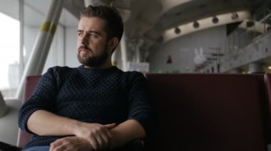 Havaalanı ve kalkış için bekleyin oturan yakışıklı sakallı adam