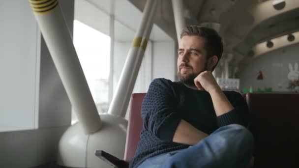 Joven esperando su vuelo en la sala del aeropuerto — Vídeo de stock