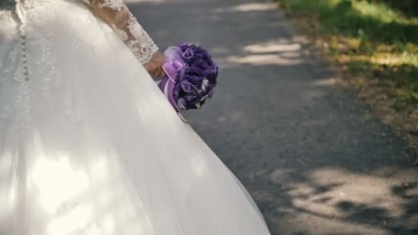 View from the back on the bride with bouquet walk in the forest — Stock Video