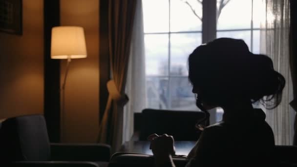 Silueta de la mujer modelo sentada frente a la ventana con fugas de luz en cámara lenta — Vídeo de stock