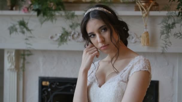 Linda noiva morena brincalhão vestindo vestido branco posando no fundo da lareira — Vídeo de Stock