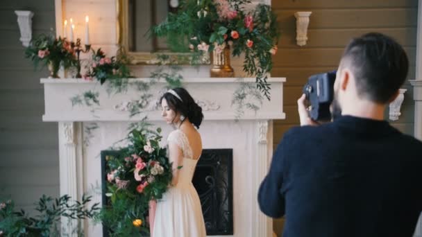 Fotograaf schieten bruid met een boeket en een open haard op de achtergrond — Stockvideo