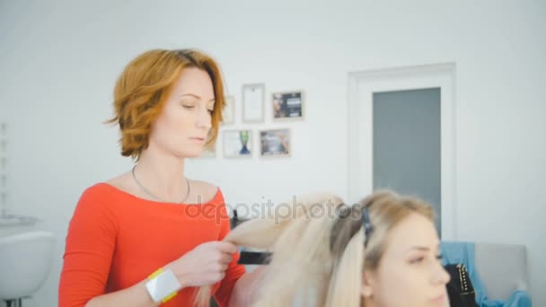 Kobiece Fryzjer luksusowy salon piękności jest stały i pracę z młodych blonde model — Wideo stockowe