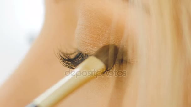 Artista de maquiagem de olho profissional aplicando pó de sombra. Cara de mulher bonita. Maquiagem perfeita. Moda de beleza. Cílios. Fechar e câmera lenta — Vídeo de Stock