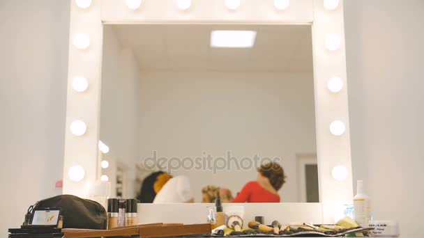 Reflejo espejo del maquillador y peluquero preparando modelo rubia en el salón de estudio en cámara lenta — Vídeos de Stock