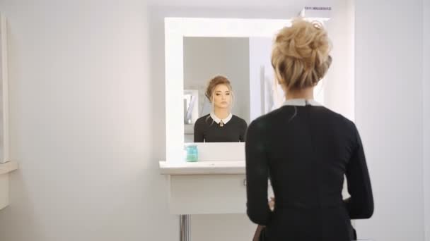 Όμορφο ξανθό μοντέλο κοιτάζοντας στον καθρέφτη στο σαλόνι ομορφιάς — Αρχείο Βίντεο