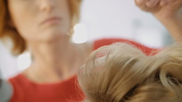 Женщина-парикмахер роскошного салона красоты стоит и работает с молодой блондинкой — стоковое видео