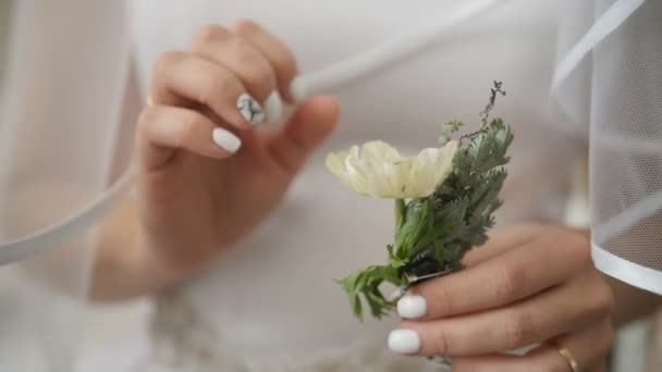 Невеста держит в руках бутоньерку. Свадебная подготовка — стоковое видео