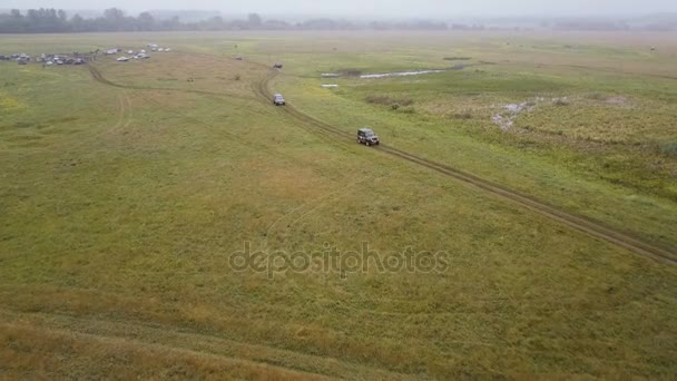 Flygfoto. Panoramautsikt över hösten landskap. Landskap med fält och träd i dimma. Drone kamera skott. Offroad Bil driver vägen från lägret — Stockvideo