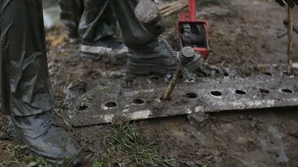 Man strike big nail with hammer, while worker uses track jack in slow motion. Try to get stucked car from mud and dirt. — Stock Video