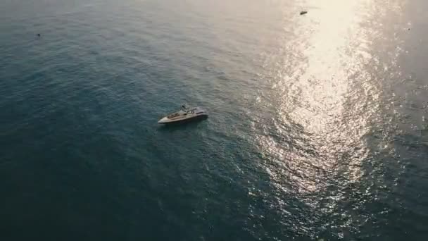 Повітряний вигляд швидкісний човен пливе біля узбережжя у спокійній воді в сонячний день. Сонячне відображення поверхні води . — стокове відео