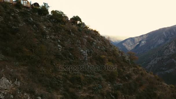 Geweldige luchtfoto openen achter houten huizen op het rotsmassief van de berg — Stockvideo